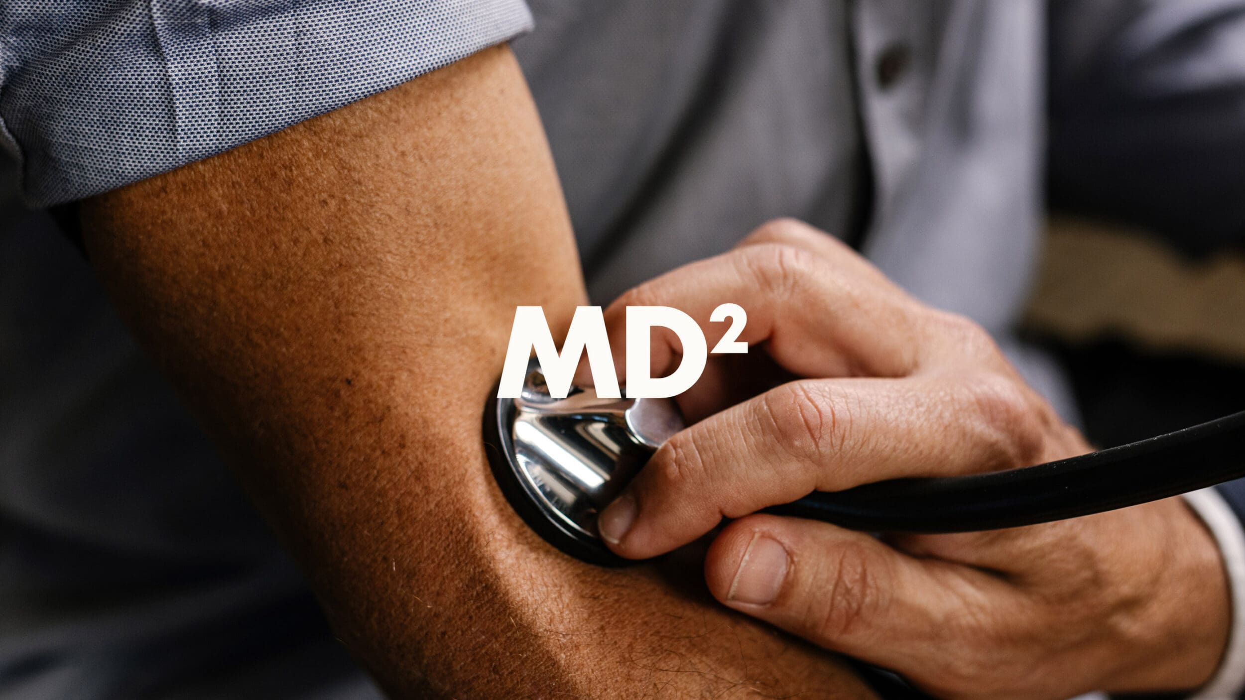 Physician from MD² gently checking a patient’s pulse during a clinical consultation, reflecting attentive and personalized medical care.