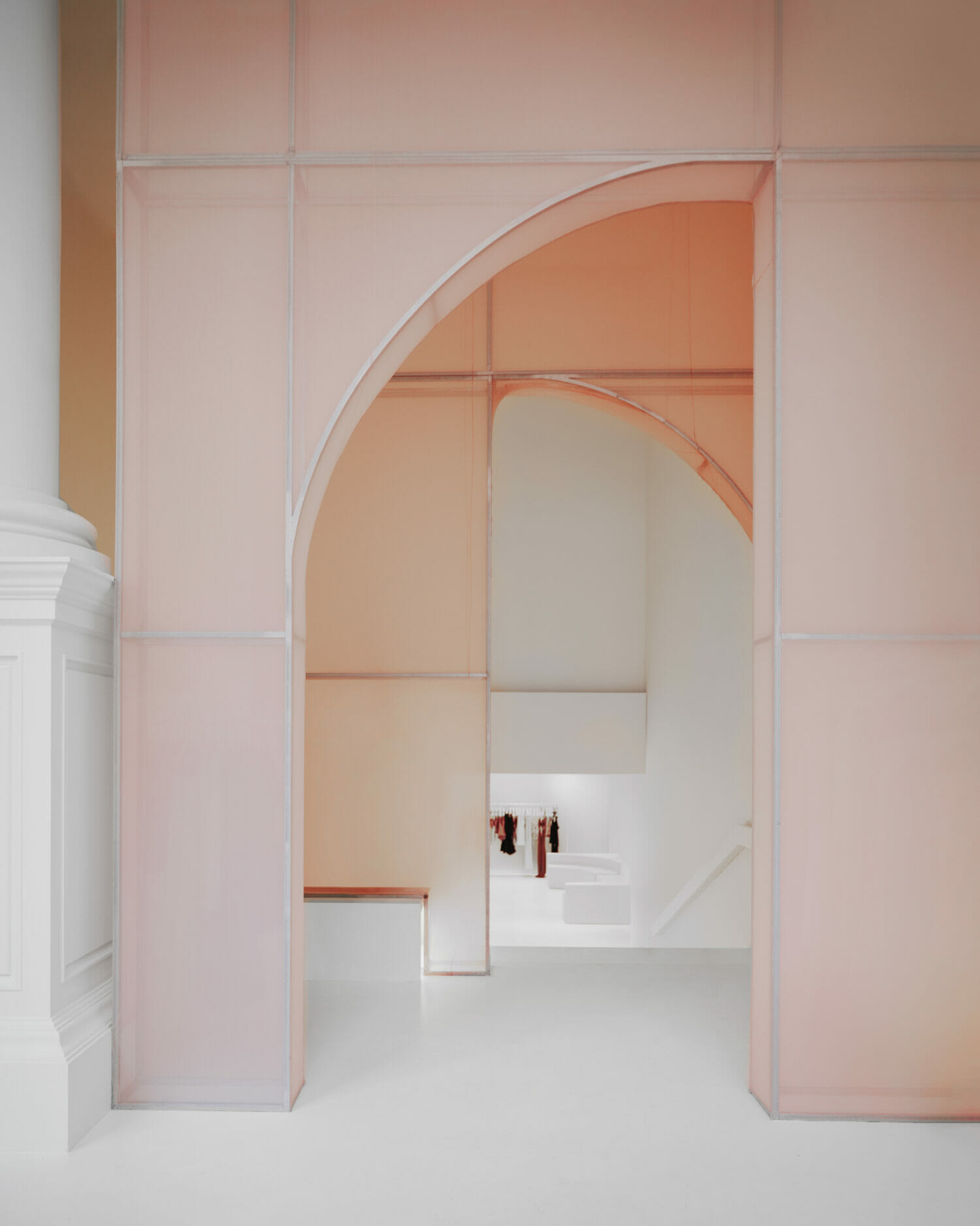 Simkhai interior with soft pink translucent archways, clean white flooring, and modern architectural detailing.