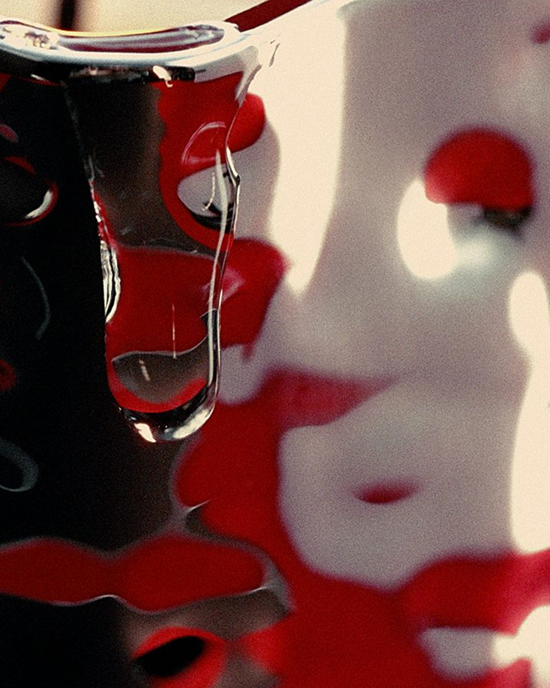Cinematic close-up featuring reflective liquid dripping over glossy black and red surfaces.