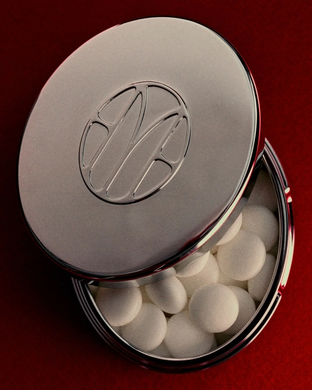 Open metallic capsule container filled with smooth white spheres