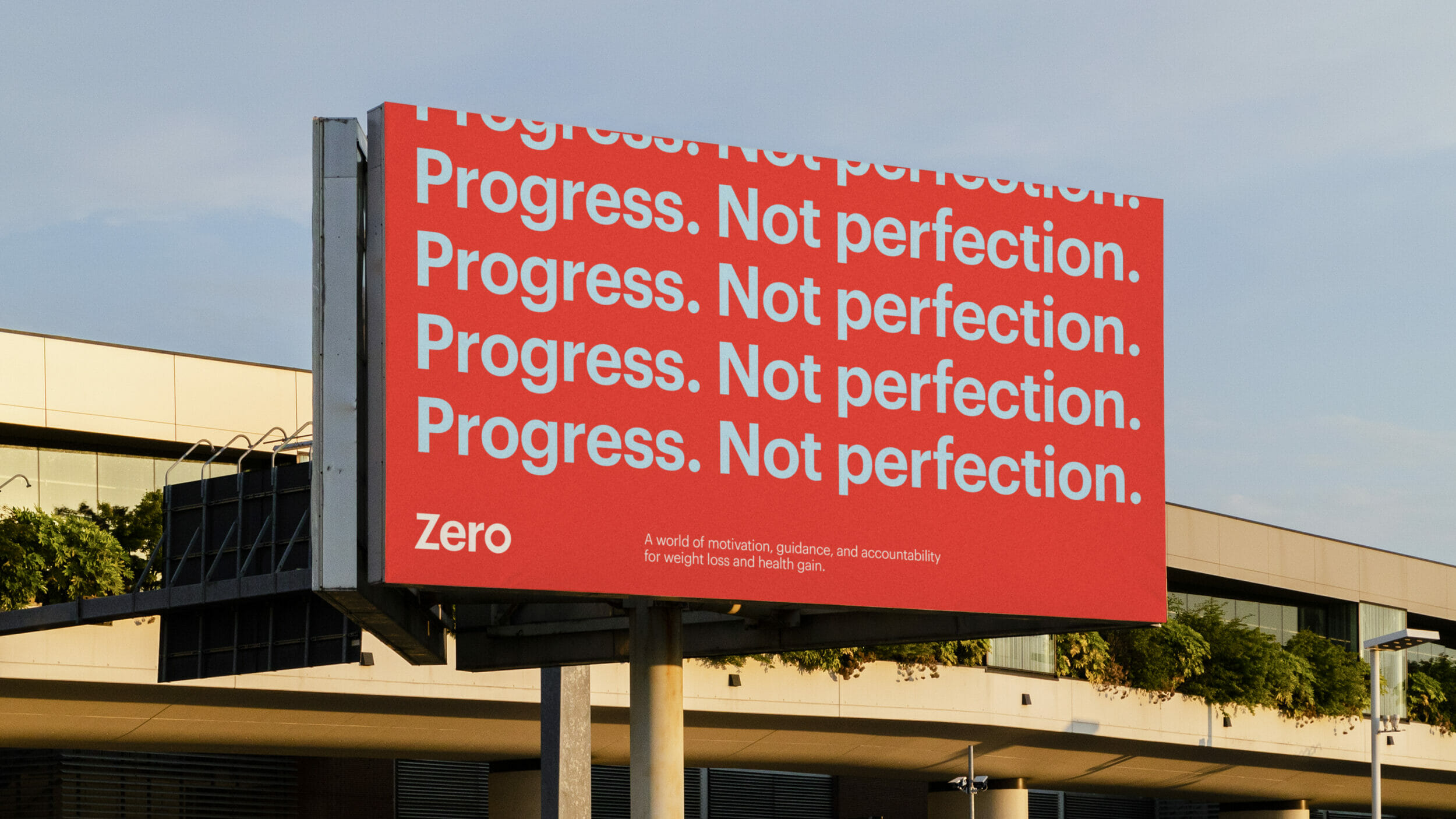 Zero billboard on a highway overpass with the phrase Progress. Not perfection.